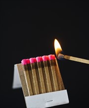 Close up of matches with one burning.
