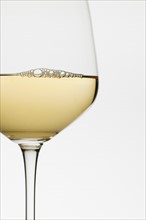 Close up of glass of white wine on white background.