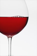 Close up of glass of red wine on white background.