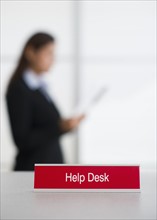 Help desk sign with defocused woman in background.