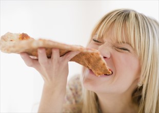 Young woman eating pizza. Photo : Jamie Grill Photography