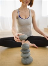 Woman preparing for meditation and stacking pebbles. Photo: Jamie Grill Photography