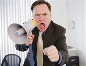 Businessman yelling through bullhorn. Photo: Jamie Grill Photography