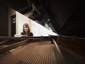 Portrait of young pianist sitting by grand piano. Photo: Mike Kemp