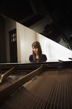 Young woman playing grand piano. Photo: Mike Kemp