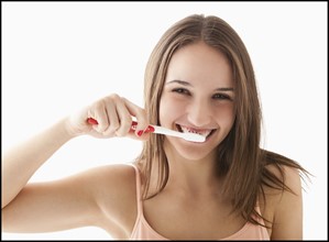 Studio portrait of young woman brushing teeth. Photo: Mike Kemp