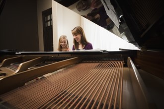 Girl (8-9) and mother playing grand piano. Photo: Mike Kemp