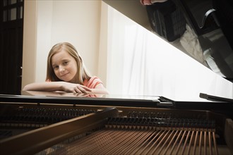 Girl (8-9) leaning on grand piano. Photo: Mike Kemp