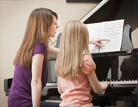 Girl (8-9) and mother playing grand piano. Photo: Mike Kemp