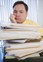 Businessman behind stack of paperwork. Photo: Jamie Grill Photography