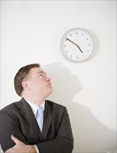 Businessman looking up at clock. Photo : Jamie Grill Photography