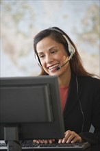 Female customer service representative with headset working on computer.