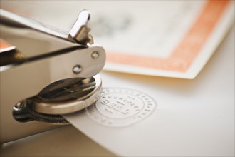 Close up of stamper making seal on paper.