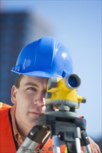 USA, New Jersey, Jersey City, construction worker in hard hat using theodolite.