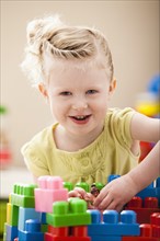 Portrait of smiling girl (2-3) playing with colorful blocks. Photo : Mike Kemp