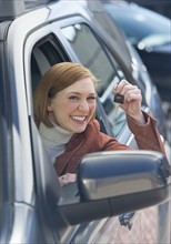Woman sitting in new car showing car key.