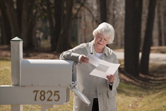 USA, Virginia, Richmond, senior woman reading letters by mailbox. Photo : Mark Edward Atkinson