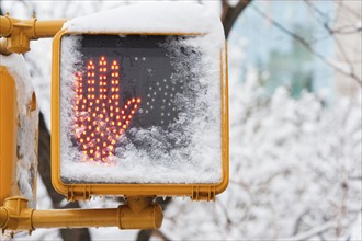 USA, New York City, New York, don't walk sign with hand covered with snow.