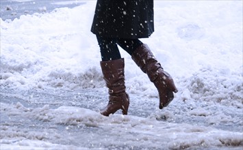 USA, New York, New York City, close up of woman's legs walking in winter slush.
