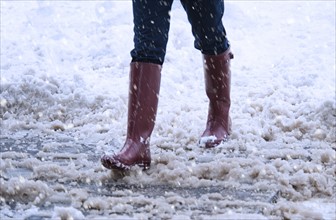 USA, New York, New York City, close up of woman's legs walking in winter slush.