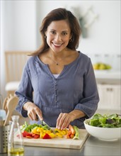 Smiling woman preparing food in kitchen.