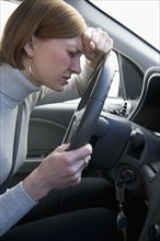 Woman driving car looking upset.