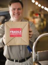 Delivery man holding box with fragile sign. Photo : Jamie Grill Photography