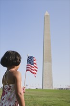 USA, Washington DC, girl (10-11) with US flag in front of Washington Monument. Photo: Chris Grill