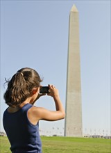 USA, Washington DC, girl (6-7) photographing Washington Monument. Photo : Chris Grill