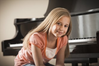 Portrait of girl (8-9) sitting by piano. Photo : Mike Kemp