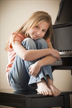 Portrait of girl (8-9) sitting by piano. Photo : Mike Kemp