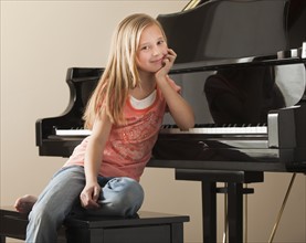 Portrait of girl (8-9) sitting by piano. Photo: Mike Kemp