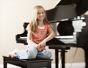 Portrait of girl (8-9) sitting by piano. Photo: Mike Kemp