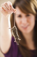 Young woman holding mouse by tail. Photo : Mike Kemp