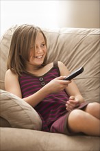 Girl (10-11) sitting on sofa, watching TV. Photo : Mike Kemp