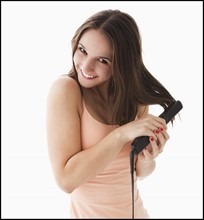 Studio portrait of young woman straightening hair. Photo: Mike Kemp