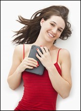 Studio portrait of young woman holding electronic organizer. Photo : Mike Kemp