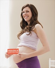 Young pregnant woman holding fragile sign. Photo : Mike Kemp