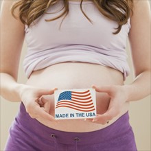 Young pregnant woman holding Made in the USA Sign. Photo: Mike Kemp