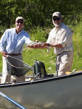 USA, Colorado, Man showing trout while standing in fishing boat. Photo : John Kelly