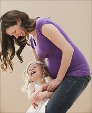 Portrait of girl (2-3) and pregnant mother embracing. Photo : Mike Kemp