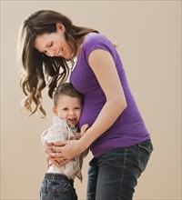 Portrait of boy (2-3) leaning on pregnant mother's belly. Photo : Mike Kemp