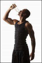 Studio shot of man drinking water from bottle. Photo : Mike Kemp