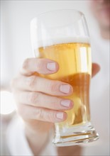 Hand holding glass of beer. Photo : Jamie Grill Photography
