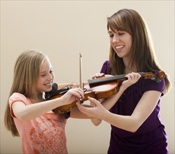 Mother teaching daughter to play violin. Photo: Mike Kemp