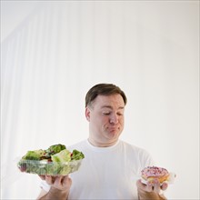 Man comparing donut and salad. Photo: Jamie Grill Photography