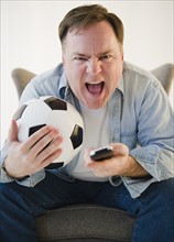 Man holding remote control and soccer ball. Photo: Jamie Grill Photography