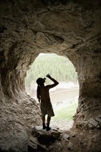 USA, Montana, Smith River, Young man drinking water in cave. Photo: Noah Clayton