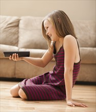 Girl (10-11) sitting on floor, watching TV. Photo : Mike Kemp