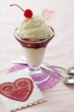 Close up of ice cream dessert with cherry on top and heart shaped cut-out.